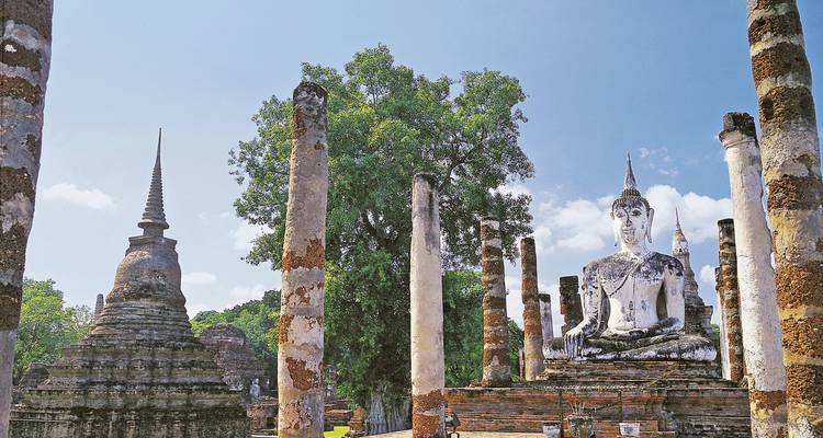Ruines de structures anciennes et une grande statue de Bouddha sous un ciel lumineux.