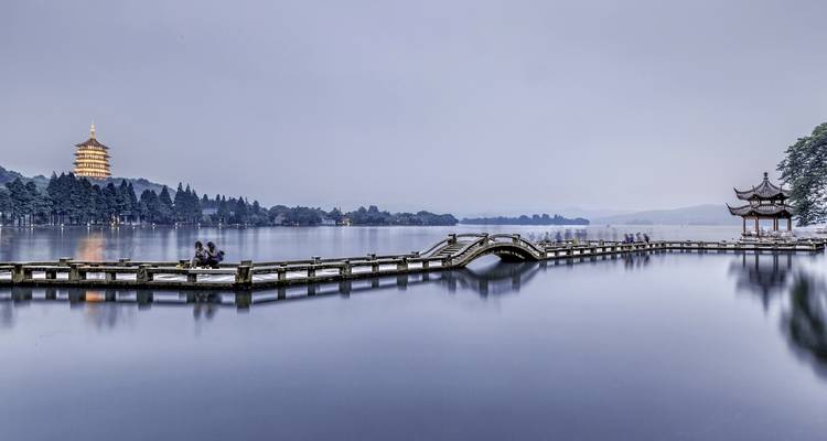 Vue élégante au bord du lac avec une pagode et une tour au loin.