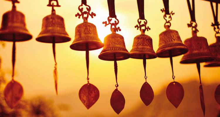 Cloches suspendues se détachant en silhouette sur un coucher de soleil en arrière-plan.