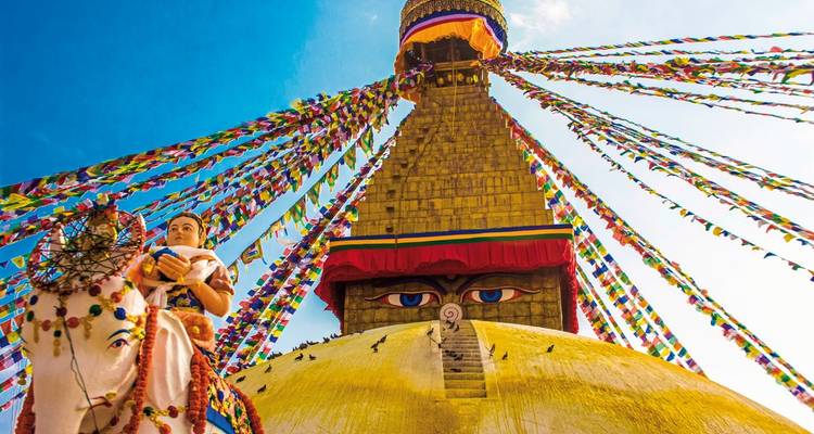 Stupa avec drapeaux de prière colorés sous un ciel bleu clair.