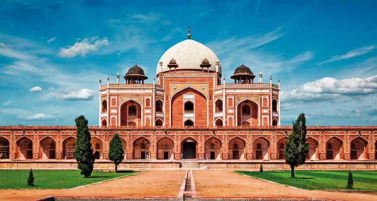 Tombeau de Humayun entouré de verdure et de ciel nuageux.