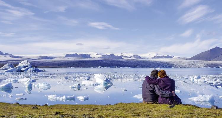 Couple s'enlaçant près d'un lagon glaciaire rempli d'icebergs.
