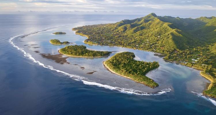 Une vue aérienne d'îles entourées d'eau bleue claire et de récifs.
