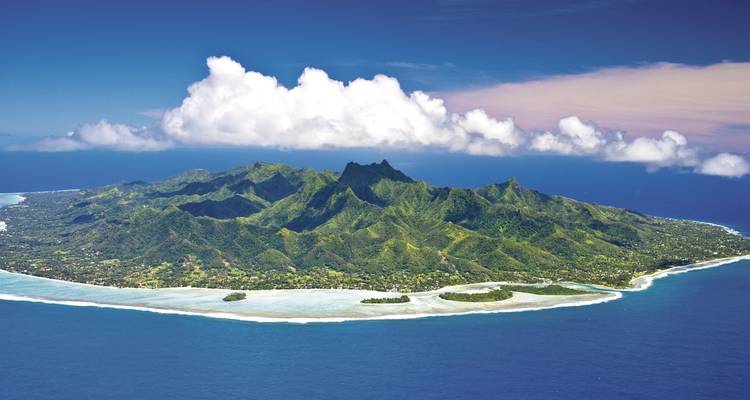 Paysage insulaire avec une végétation luxuriante et des montagnes entourées par l'océan.