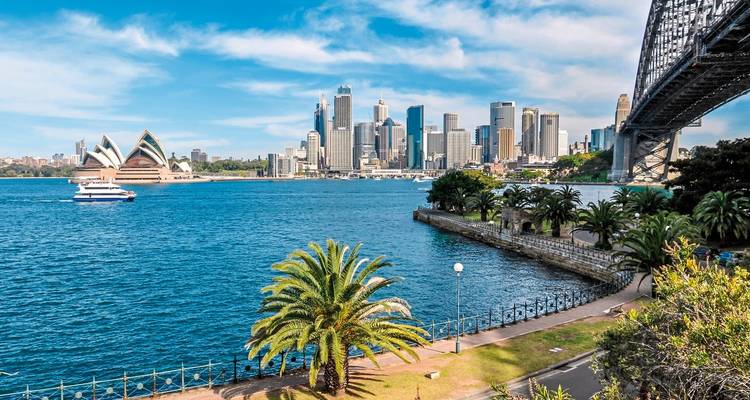 El horizonte de Sydney con la Ópera y el Puente del Puerto desde un parque.