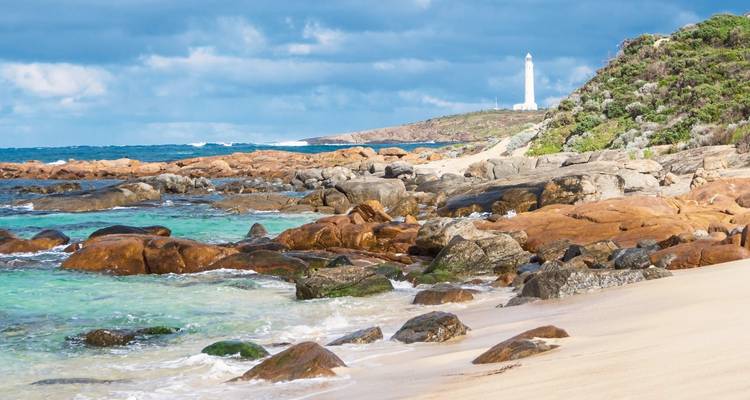 Plage avec phare sur une colline