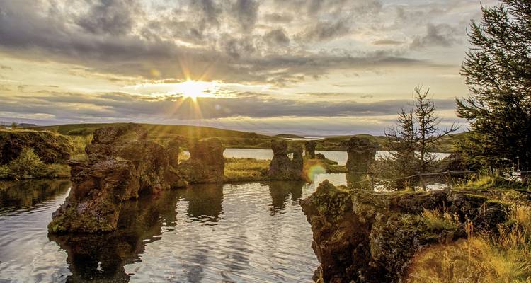 Formations rocheuses dans un lac avec un coucher de soleil lumineux.