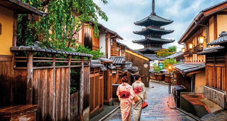 Zwei Frauen in farbenfrohen Kimonos gehen nach Regen die traditionelle Yasaka-Pagoden-Gasse in Kyoto hinunter.