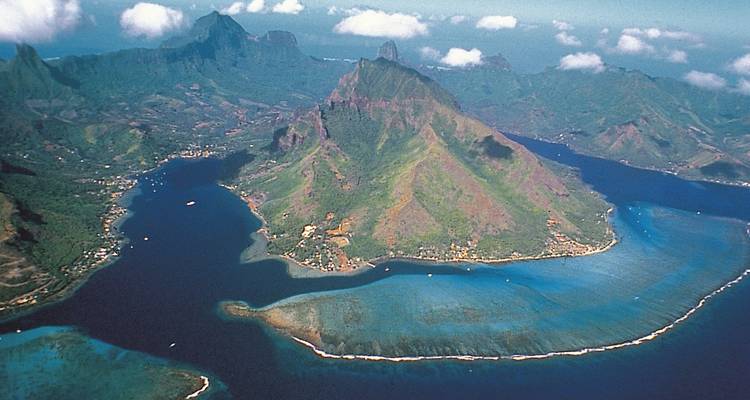 Vue aérienne d'une île montagneuse luxuriante et de l'océan environnant.