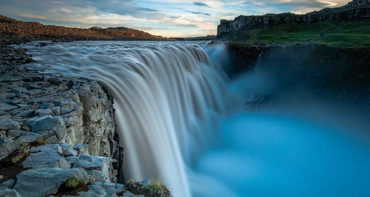 Cascade puissante dévalant des falaises rocheuses sous un ciel bleu.