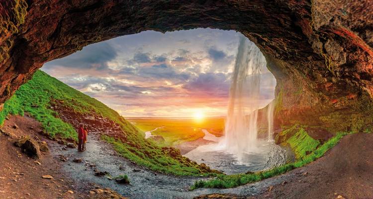 Vue depuis l'arrière d'une cascade au coucher du soleil, avec des personnes debout à proximité.