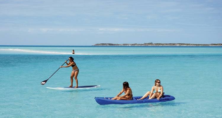 Mensen die peddelen en kajakken op helder turquoise water.
