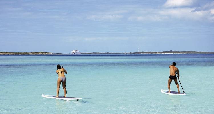 Dos personas haciendo paddleboard en agua azul cristalina.