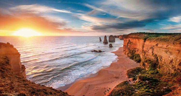 Sonnenuntergang über einer malerischen Küstenlandschaft mit Felsformationen.