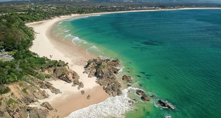 Vue aérienne d'une plage avec une eau turquoise claire et des formations rocheuses