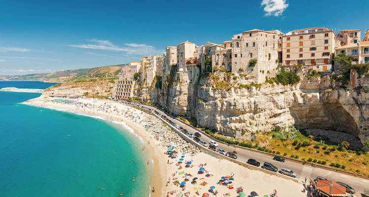 Ciudad costera con edificios en acantilados que dan a un mar turquesa.