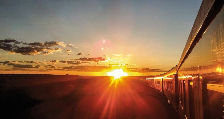 Trein die reist tijdens een prachtige, kleurrijke zonsondergang.