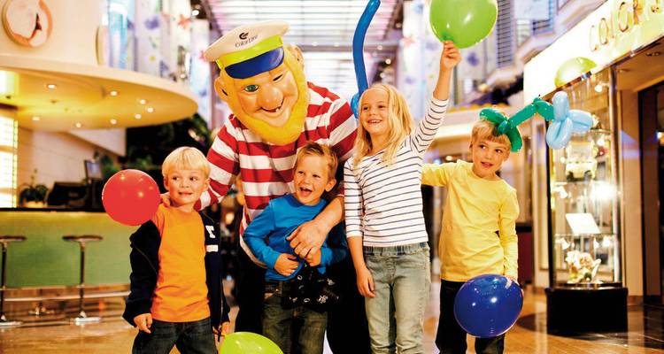 Vier kinderen met kleurrijke ballonnen en een mascotte.