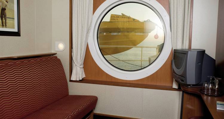 Binnen in een scheepshut met uitzicht door een patrijspoort.