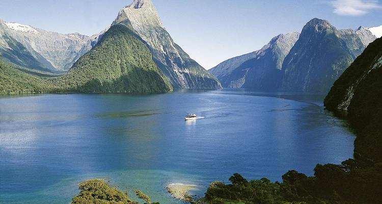 Vue panoramique de Milford Sound avec un bateau de croisière et les montagnes environnantes.