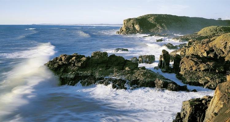 Côte rocheuse avec des vagues qui se brisent sur le rivage.