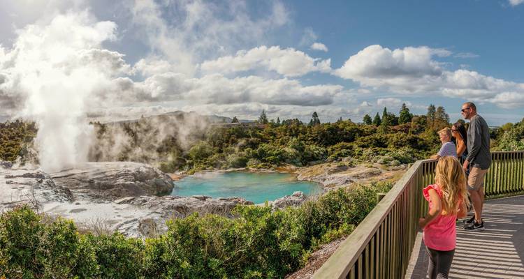 A family observing a geyser in a geothermal park.