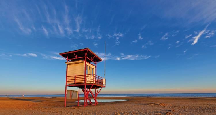 Strandgezicht met reddingstoren tijdens zonsondergang.