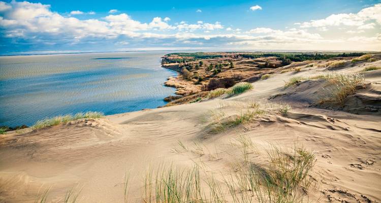 Zandduinen die uitkijken over een grote watermassa.