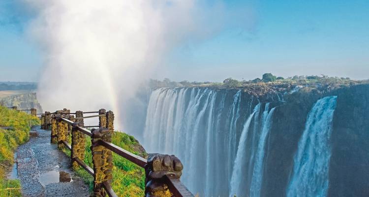 Victoria Falls with a rainbow, viewed from a walking path.