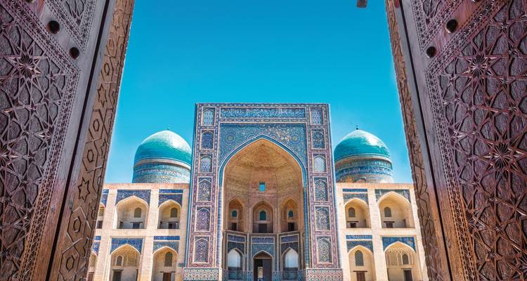 Decorated entrance leading to a historic building with blue domes.