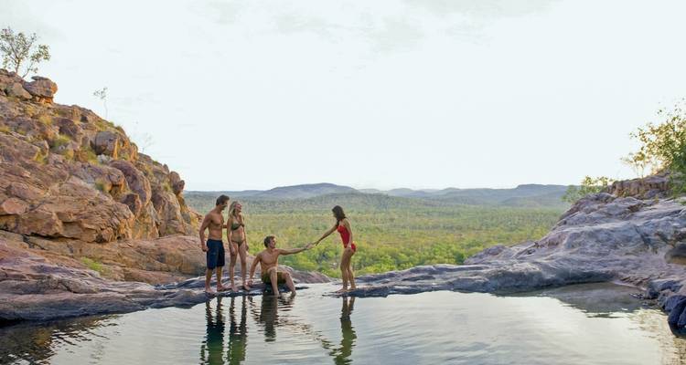 People enjoying by a natural rock pool with scenic views of landscape.