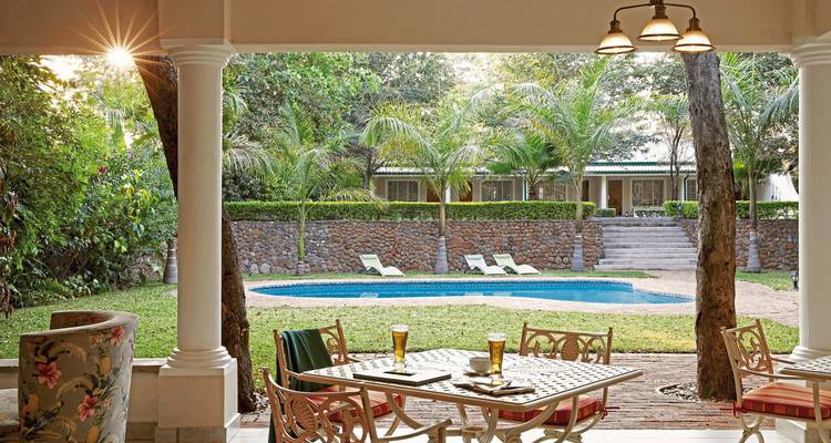 Een stijlvolle patio met uitzicht op een zwembad met weelderige tuinen erachter.