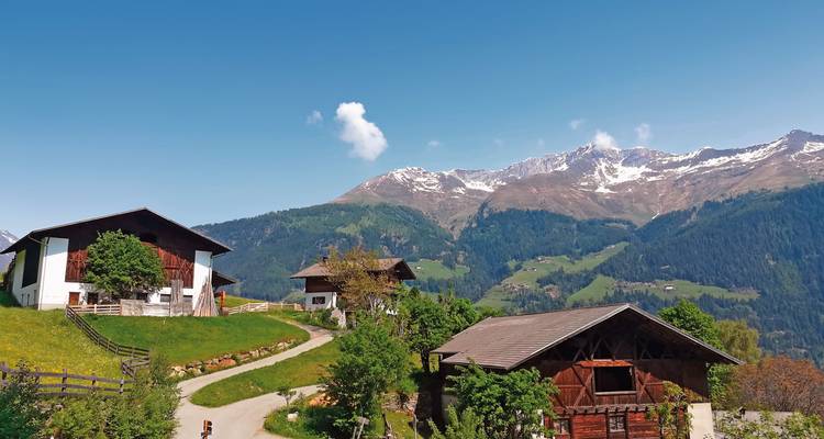 Rustikale Bauernhäuser in einem Tal mit bergiger Kulisse.