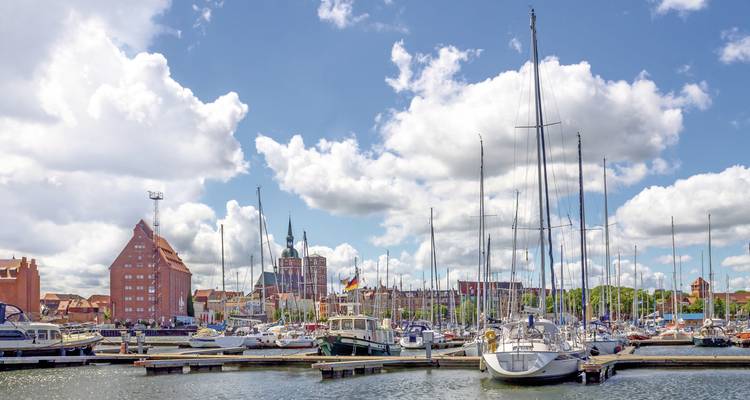 Marina pleine de yachts avec une ville historique en arrière-plan.