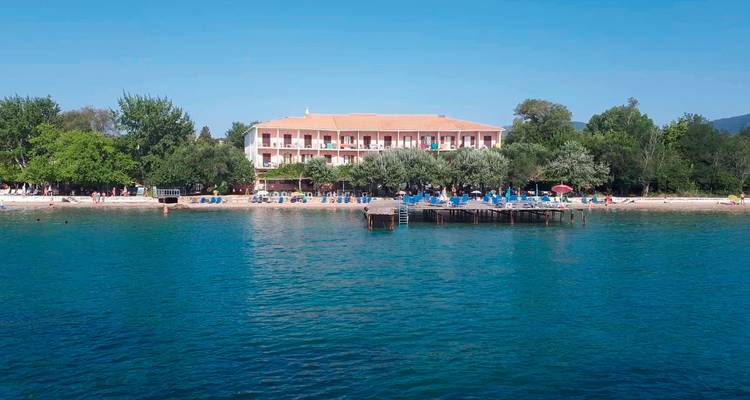 Bâtiment près d'une plage avec des baigneurs de soleil et de l'eau bleue.