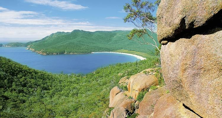 Paysage côtier pittoresque avec une baie incurvée et des collines verdoyantes.
