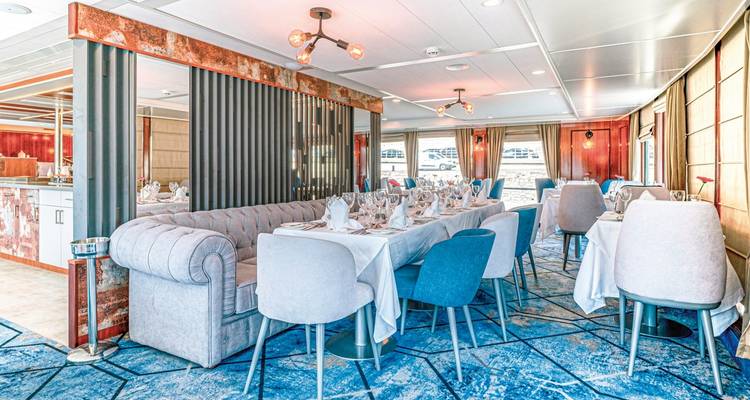 Elegant dining room with set tables and large windows.