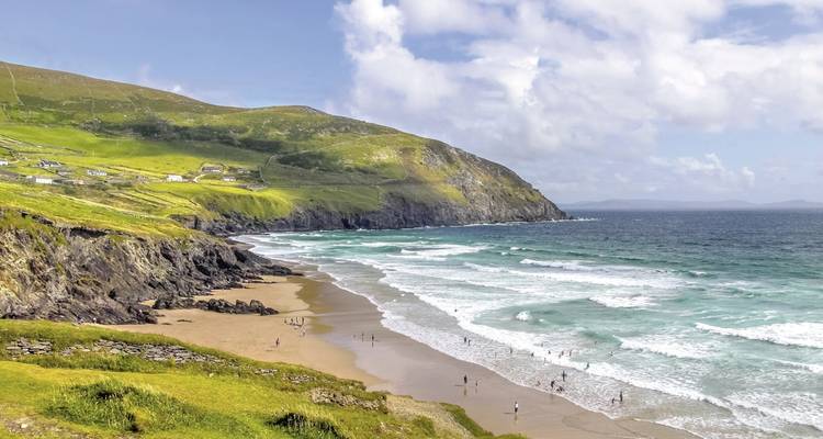 Une plage avec des gens le long du rivage avec des falaises rocheuses.