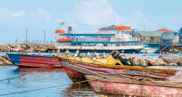 Des bateaux colorés flottant près du rivage avec un grand ferry en arrière-plan.