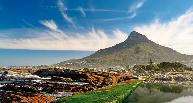 Coastal landscape with a mountain peak in the background and rocks in the foreground.