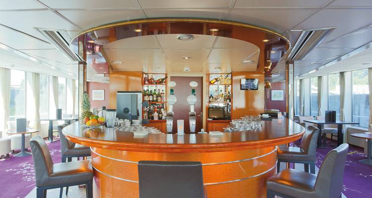 Intérieur d'un espace bar sur un bateau de croisière fluviale avec des chaises et de la décoration.