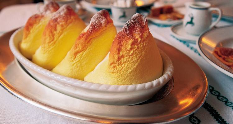 A dish of soufflés on a dining table with elegant dishware.