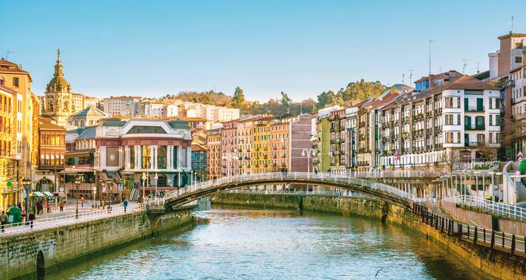 River view with a historic stone bridge and colorful houses.