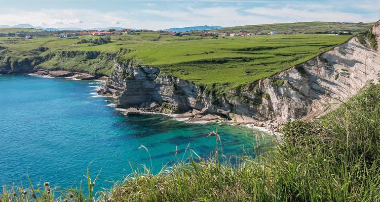 Cliffside with rolling green plains meeting the ocean.