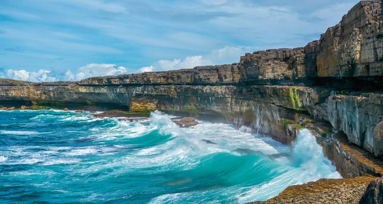 Wellen, die gegen steile Klippen krachen.
