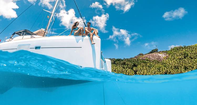 Couple assis sur un yacht au-dessus d'une eau bleue cristalline.