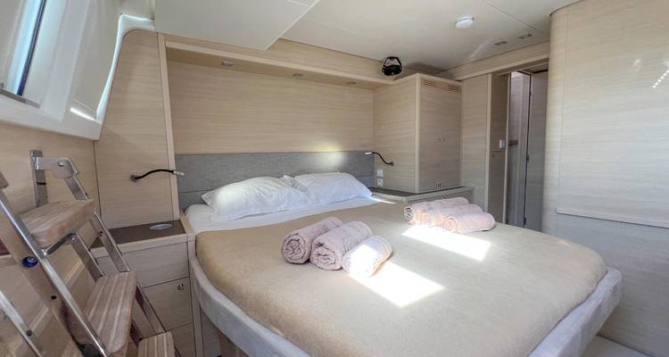 Lichte hutsenhut met tweepersoonsbed, opgerolde handdoeken en licht houten meubels op jacht