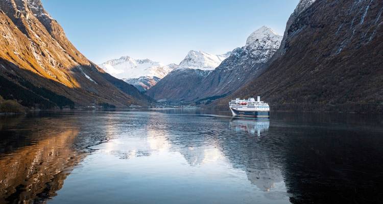 Fjord norvégien avec un navire et des montagnes enneigées.