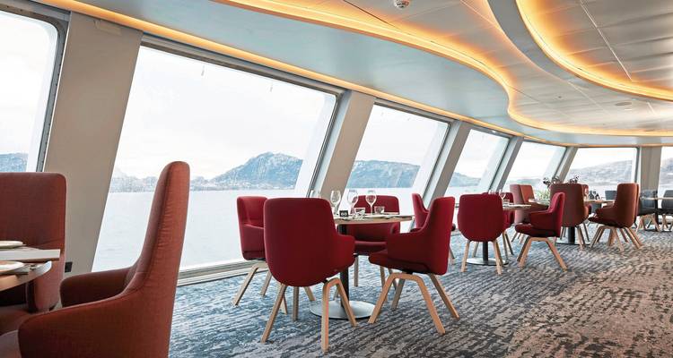 Salle à manger moderne avec de grandes fenêtres et des chaises rouges sur un navire.