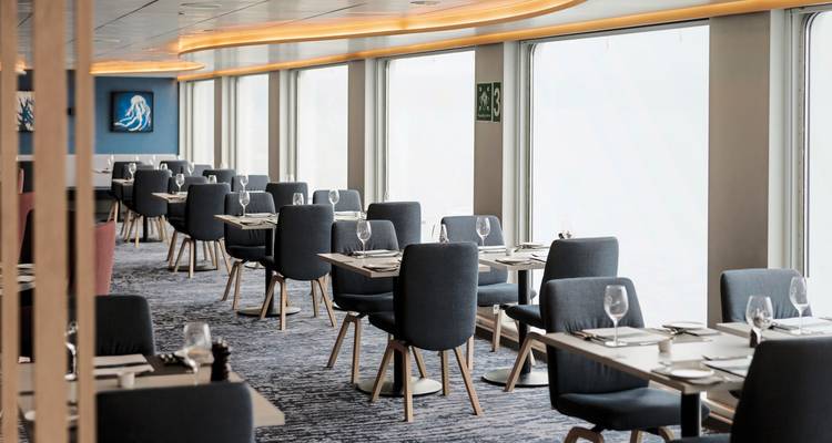Zone de restauration moderne et élégante sur un navire avec des tables dressées et de grandes fenêtres.